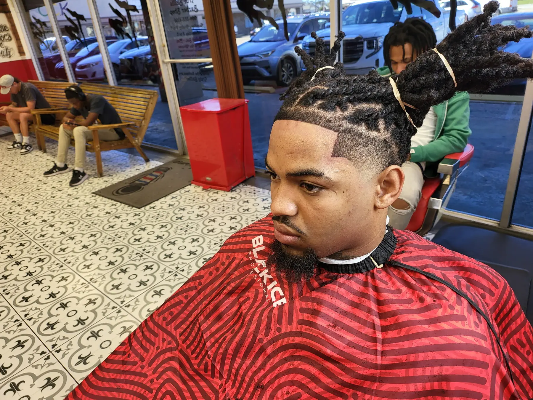 True Skills client with tied locs, a crisp lineup, and a smooth temple fade